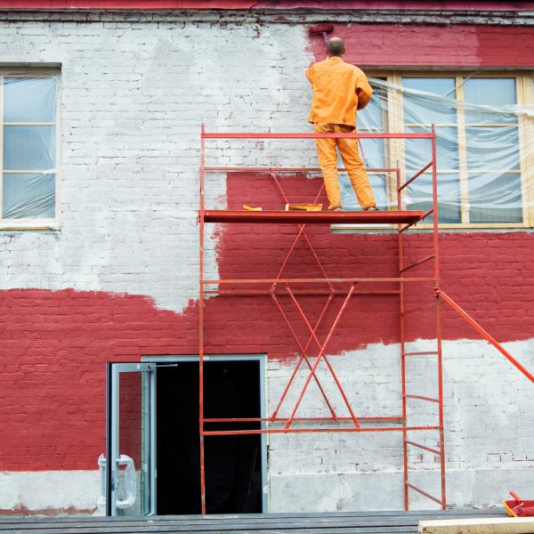 Man painting a brick wall in red