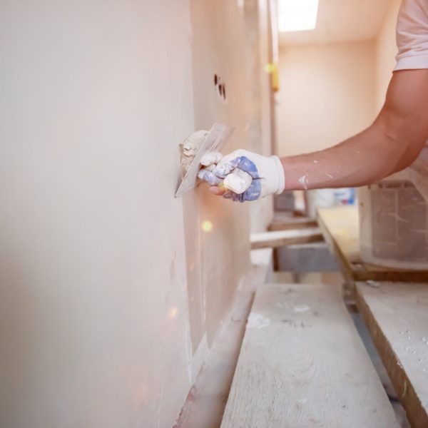 young professional construction worker plastering on gypsum walls inside the new big modern two levels apartment